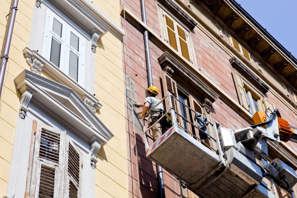 Spachtelarbeiten an der Fassade mit einem Krankorb